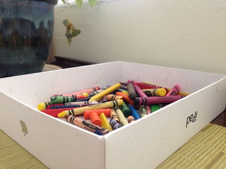 An open box of colourful wax crayons