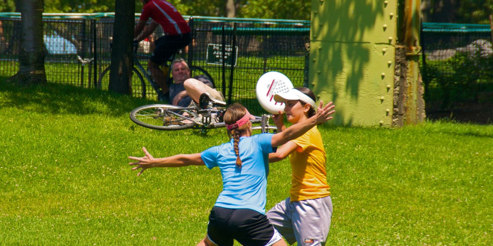 Players catching a flying disc during an Ultimate game in a park