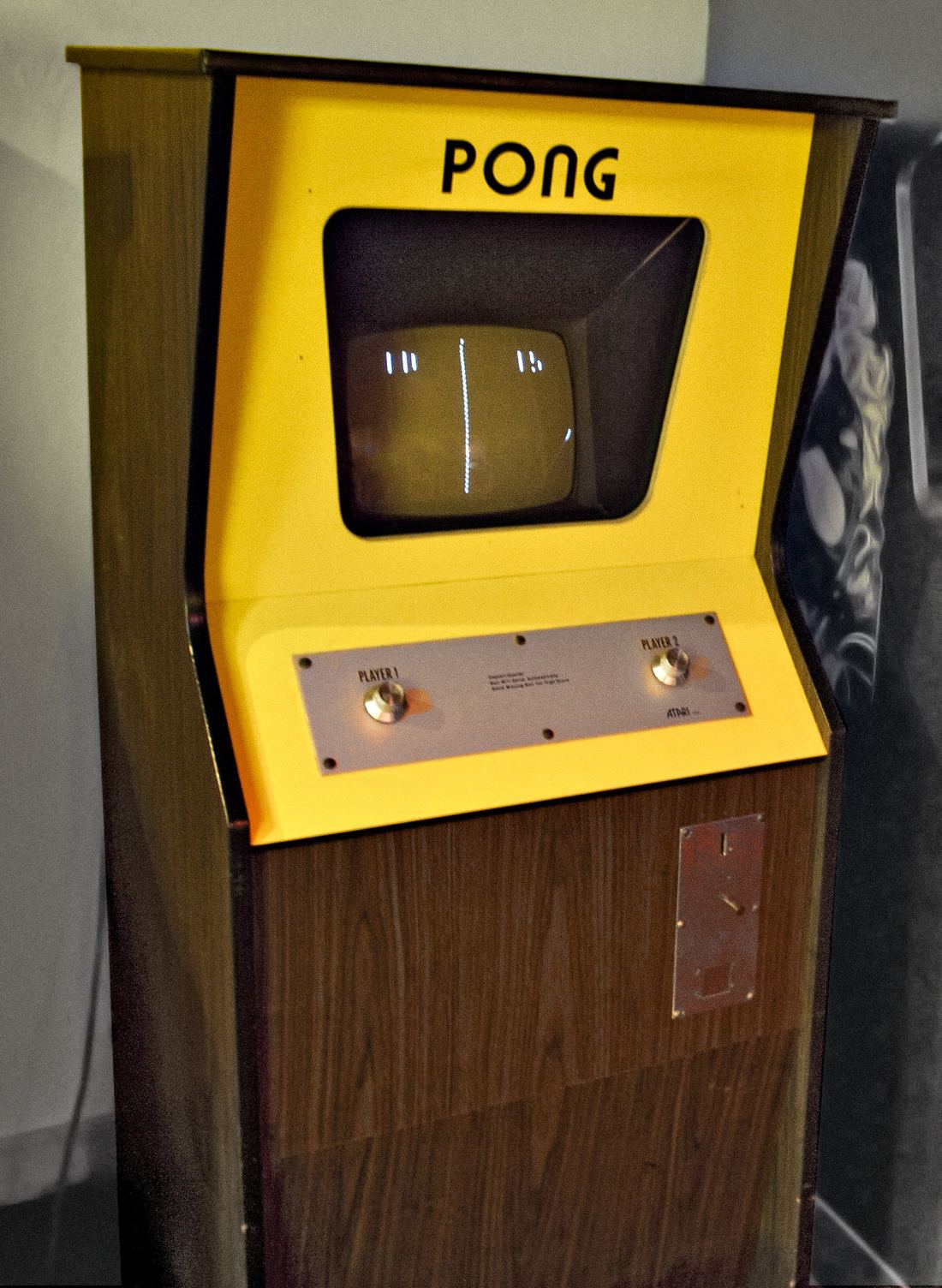 An original yellow and woodgrain Atari Pong arcade cabinet with a small black and white screen