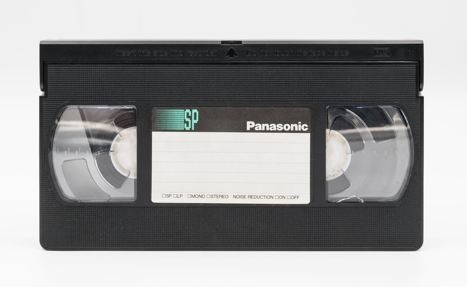 A black VHS videocassette with clear reel windows and a white label area, on a white background